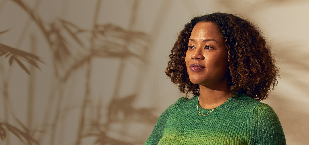 Sydney stoi w pomieszczeniu i spogląda w prawo. Na jej twarzy maluje się pewność siebie.