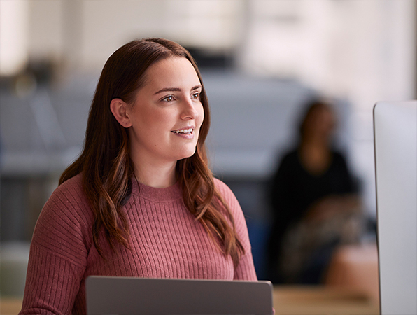 一位 Apple 軟體和服務團隊的員工正在使用 MacBook，並且看向一旁。