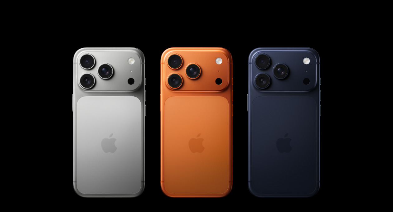 Vista traseira de três modelos iPhone 17 Pro: prateado, laranja cósmico e azul escuro, com o sistema de câmaras Pro Fusion no canto superior esquerdo, 3 lentes, microfone, flash e logótipo Apple no centro