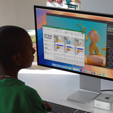 Egy nő Excel-táblázaton dolgozik Macen a munkahelyi íróasztalánál ülve. Az Excel-táblázat a negyedik negyedéves értékesítést követi nyomon. Az Excel-táblázat ablaka mögött egy Pixelmator Pro-ablak van.