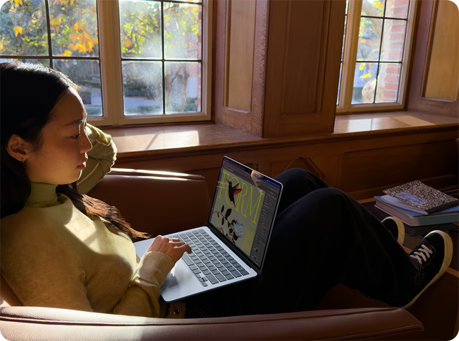 A person sitting in a chair using their MacBook Air