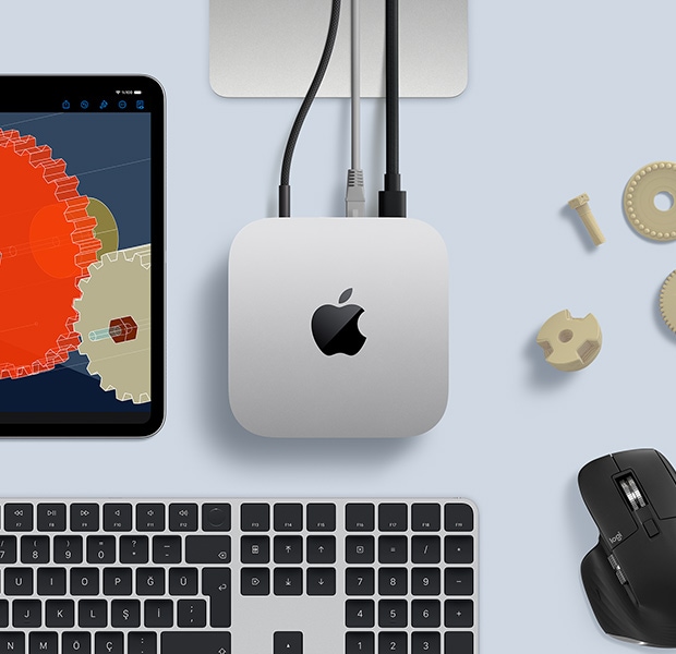 Gümüş rengi Mac mini, siyah ve gümüş rengi kablosuz klavye, siyah bir mouse ve bir iPad’in bulunduğu masa düzeninin üstten görünümü