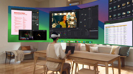 一個人戴著 Apple Vision Pro 坐在桌前，面前是打開的 13 吋 MacBook Pro，螢幕內容以超廣角曲面顯示器方式投影在房間內