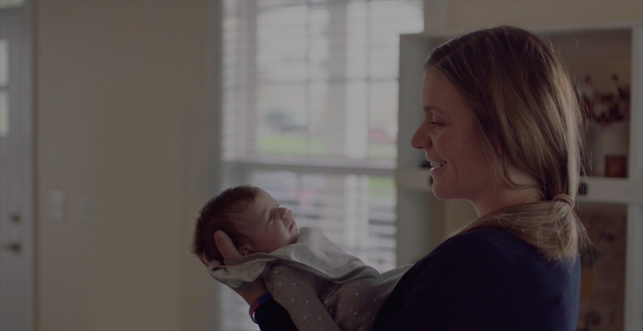 Eine Mutter, die ihr Neugeborenes anlächelt.