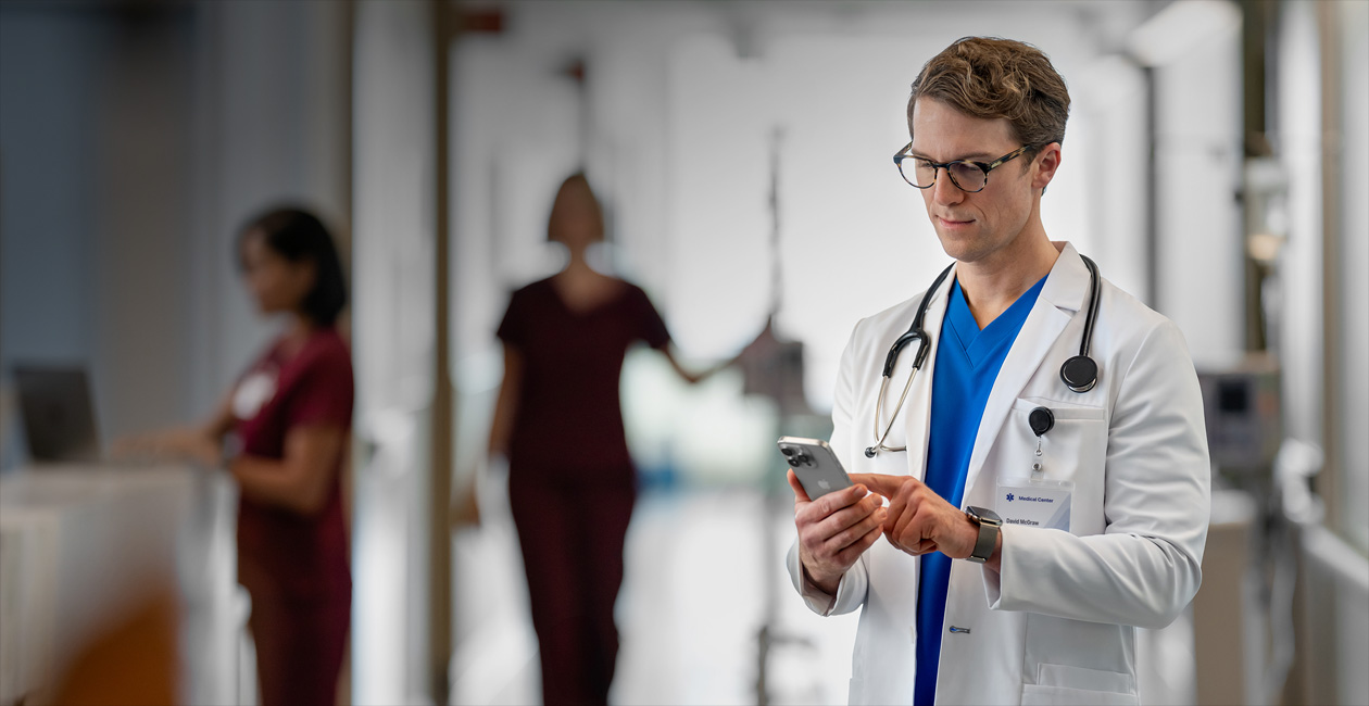 Ein Arzt schaut in einem Krankenhaus auf sein iPhone.