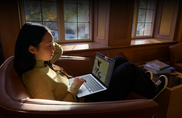 椅子に座ってMacBook Airを使っている人物