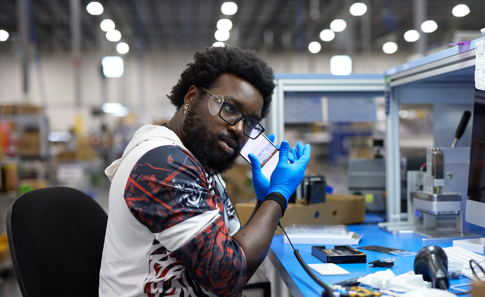 An employee sits at a work station, holding a device to their ear